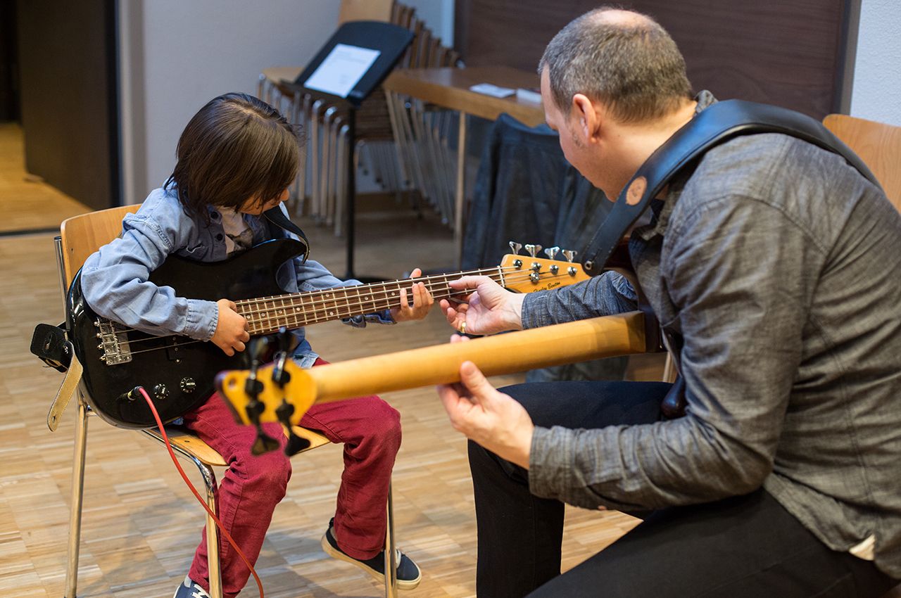 Lehrer erklärt dem Kind die E-Gitarre