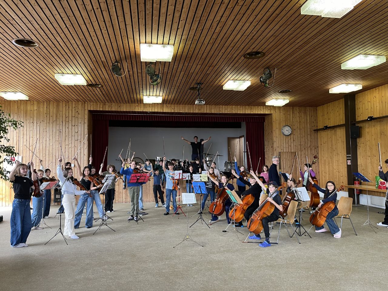 Die jungen Streicher:innen des Beatenberglagers 2024 im Musiksaal in Beatenberg an ihren Instrumenten - sie schauen alle in die Kamera.