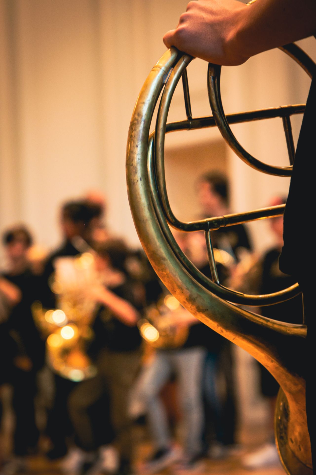 Eine Person hält ein Horn, im Hintergrund sind Kinder des Hornensembles auf der Bühne des Grossen Saals.